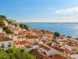 Illustration of Terracotta rooftops above the Tagus in Lisbon; representative Alfama panorama, no church or exact lookout claimed.