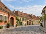 Illustration of Pastel houses along a cobbled street in Sibiu, central Transylvania; representative Lower Town streetscape, no exact street claimed.
